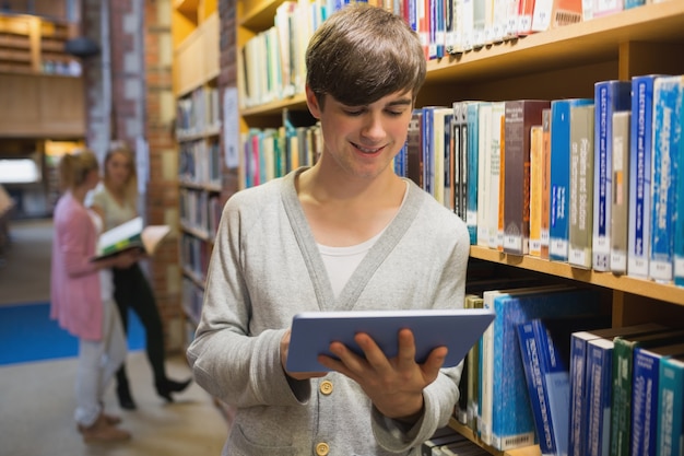 Studente che utilizza il pc della compressa che sta nella biblioteca