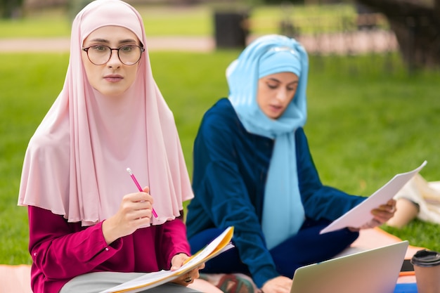 Studente con gli occhiali. Studente musulmano diligente con gli occhiali che si sente premuroso mentre si prepara all'esame