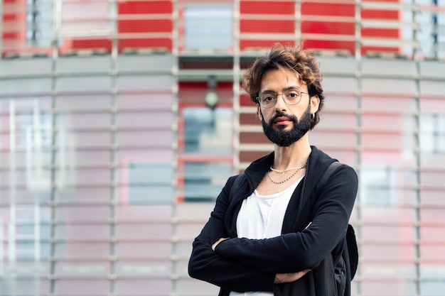 Studente con occhiali e barba con le braccia incrociate