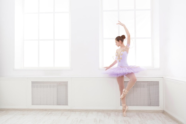 Studente di balletto che si esercita in costume di balletto, in piedi sulle punte dei piedi. Giovane ballerina adolescente che pratica la danza classica in studio prima della performance