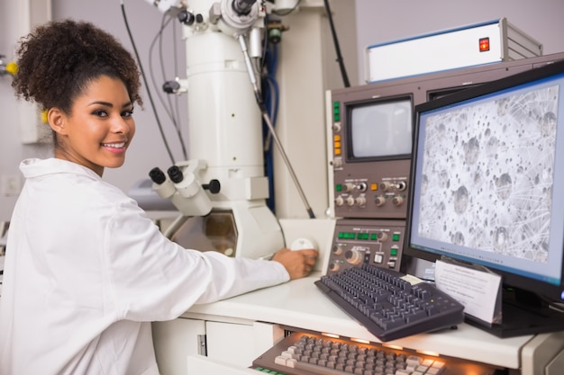 Studente di biochimica usando grande microscopio e computer