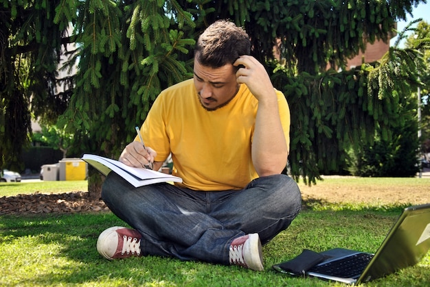 Studente di college che si trova sull&#39;erba al sole