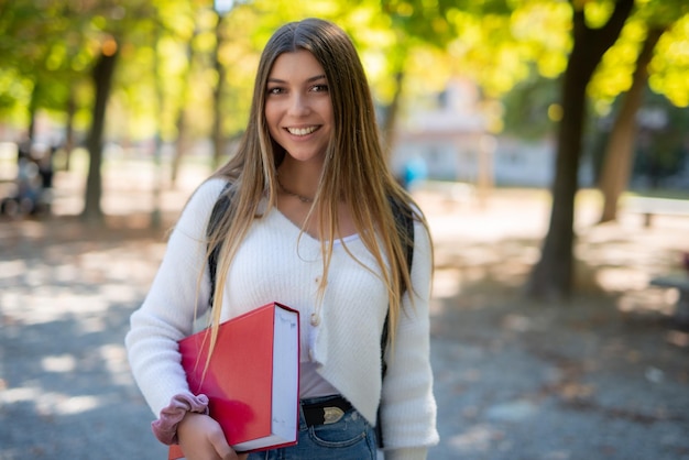 Studente di college femminile sorridente che cammina all'aperto in un parco