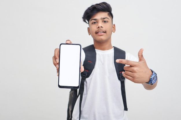 Studente di college indiano che mostra lo schermo mobile su sfondo bianco.