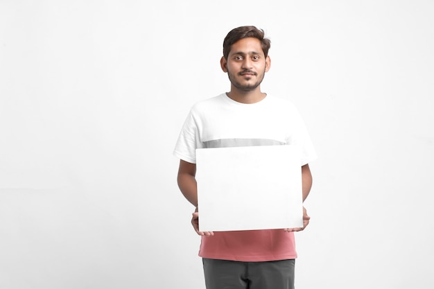 Studente di college maschio indiano che mostra manifesto in bianco