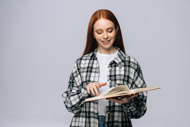 Studente di college sorridente della giovane donna che gira le pagine del libro durante la lettura