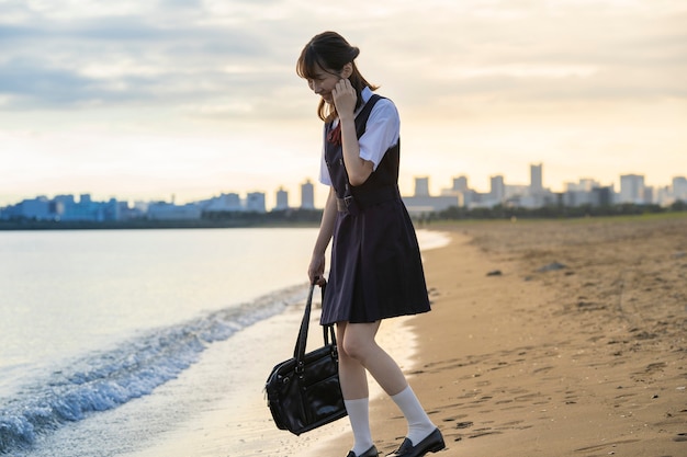 Studente di liceo femminile asiatico che cammina sulla spiaggia