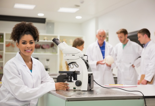 Studente di medicina felice che lavora con il microscopio