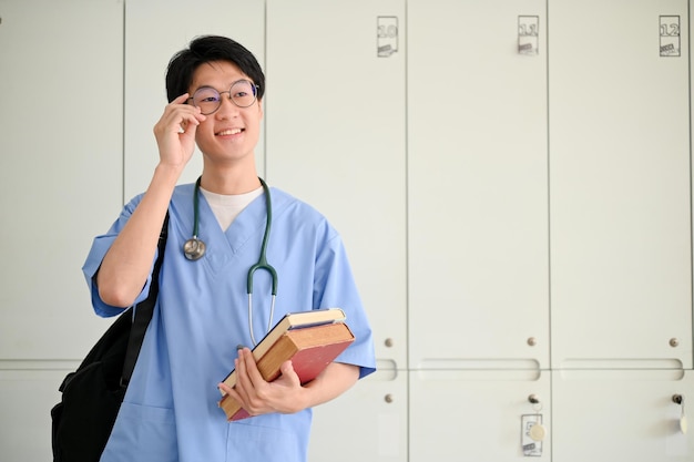 Studente di medicina maschile asiatico intelligente in uniforme si trova nello spogliatoio di uno studente di medicina