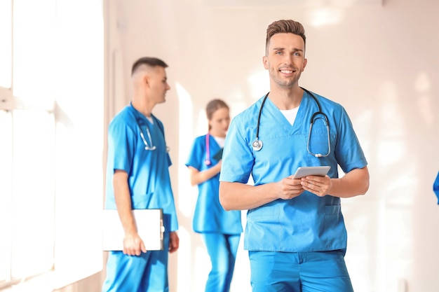 Studente di medicina maschio con computer tablet nella hall della clinica