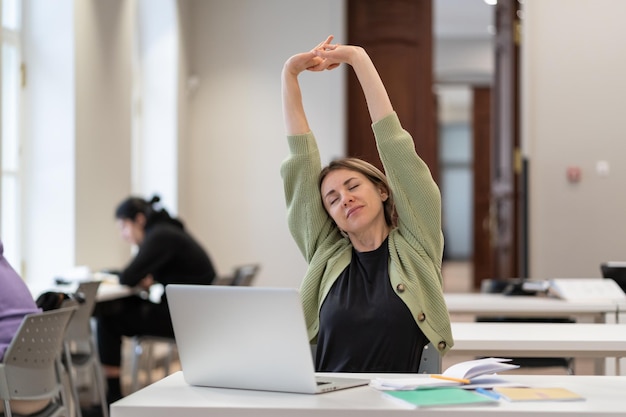 Studente di mezza età che riscalda il corpo e i muscoli in classe sentendosi soddisfatta del lavoro svolto