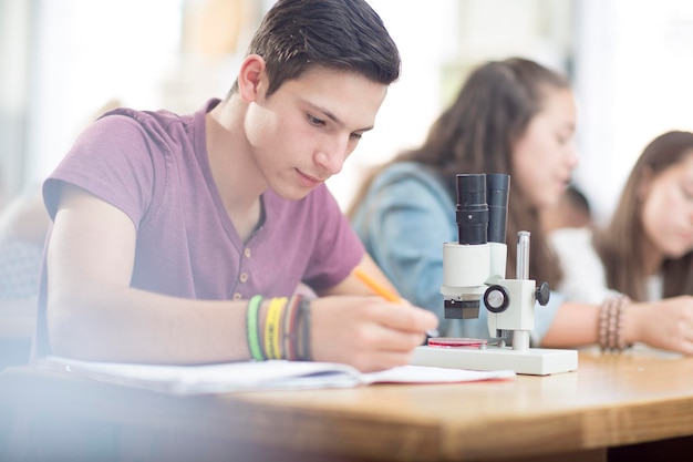 Studente di scienze che lavora in classe con il microscopio