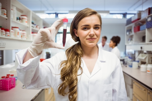 Studente di scienze piuttosto sorridente e mostrando la fiala