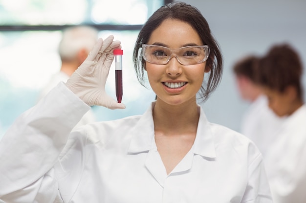 Studente di scienze piuttosto sorridente e mostrando la fiala