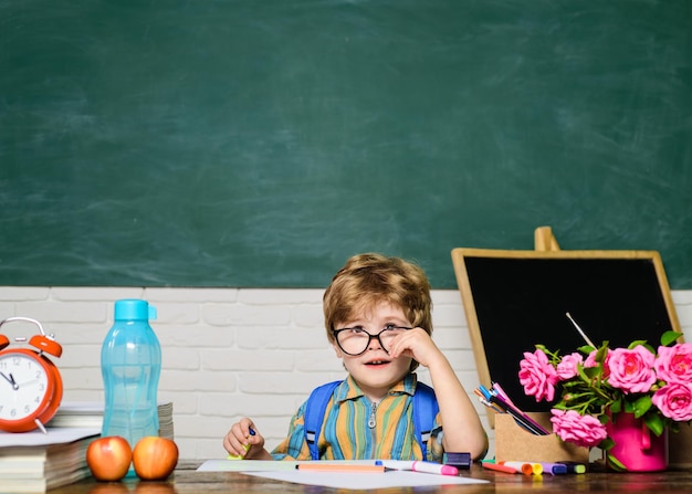 Studente di scuola elementare che disegna sul posto di lavoro bambino carino che fa i compiti