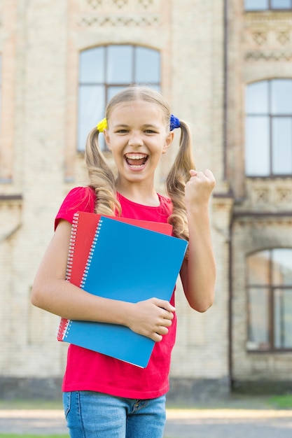 Studente di scuola secondaria Carino sorridente piccolo bambino tenere libri istituto di istruzione sfondo Adorabile bambina studentessa Lingua di studio Concetto di istruzione scolastica Carino piccolo topo di biblioteca