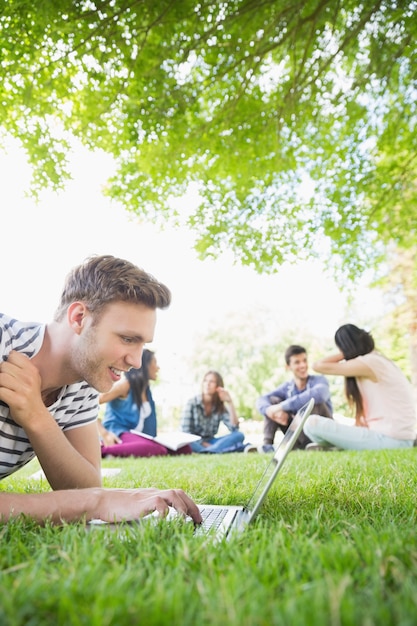 Studente felice che utilizza il suo computer portatile all&#39;esterno