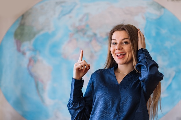 Studente felice con una mappa del mondo sul muro