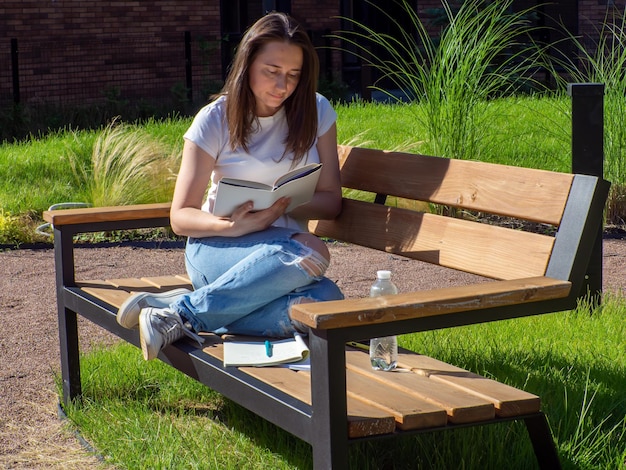 Studente femminile che studia su una panchina nel campus