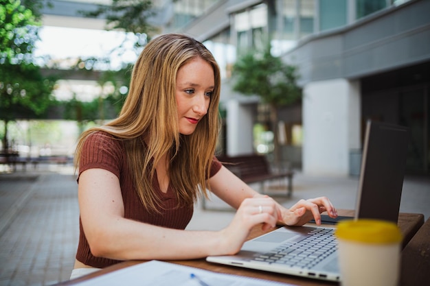 Studente giovane donna che lavora utilizzando il suo computer portatile nel campus dell'università