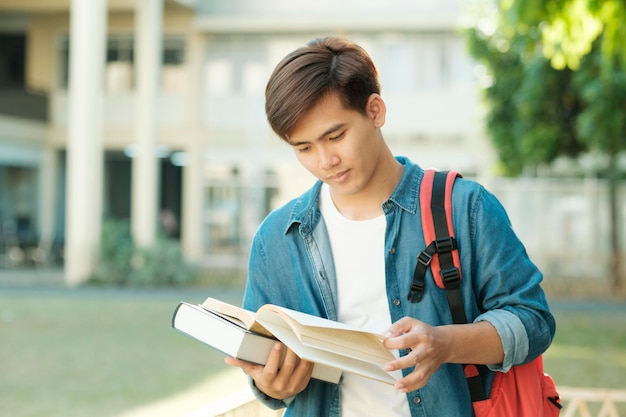 Studente in piedi all'aperto e in possesso di libri