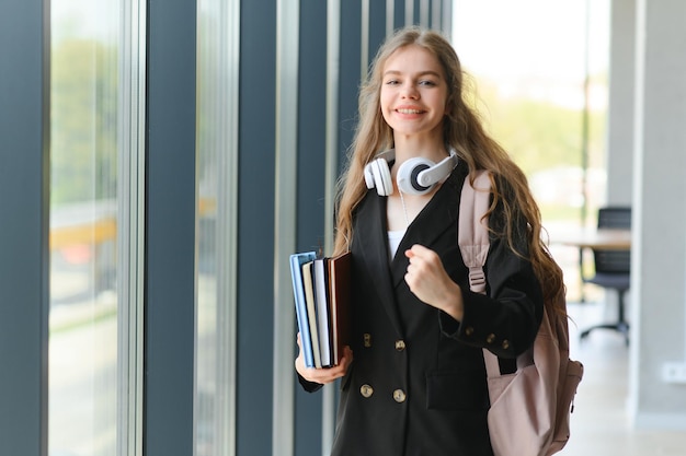 Studente in piedi con libri e zaino a scuola