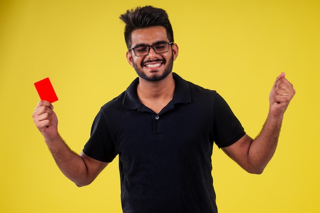 Studente in possesso di una carta di plastica su sfondo giallo in studio