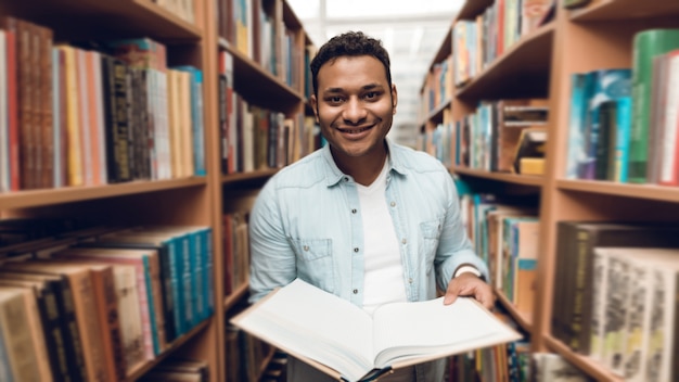 Studente indiano etnico della corsa mista in navata laterale del libro della biblioteca.