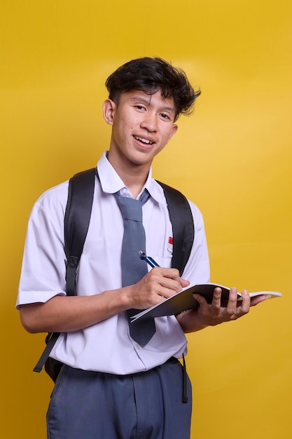 Studente indonesiano di scuola superiore in uniforme che studia e scrive sul libro