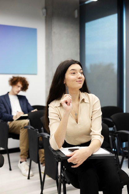 Studente interessato ascoltando lezione seduto nella moderna sala studio Donna seduta alla riunione