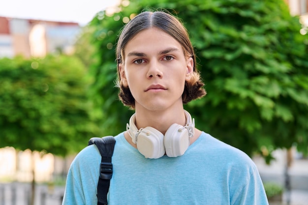 Studente maschio adolescente serio che esamina macchina fotografica all'aperto