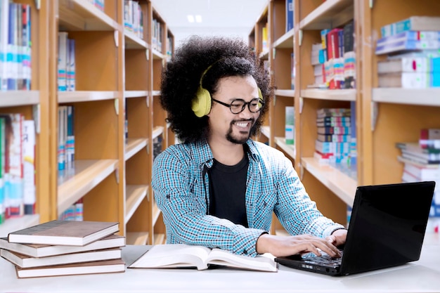 Studente maschio che ascolta musica in biblioteca