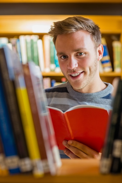 Studente maschio leggendo un libro in biblioteca