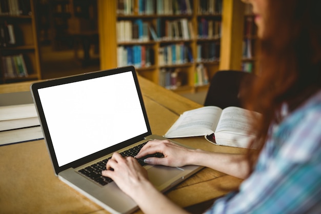 Studente maturo che studia nella biblioteca con il computer portatile