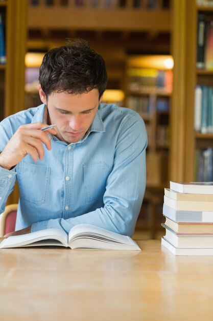 Studente maturo serio che studia allo scrittorio delle biblioteche