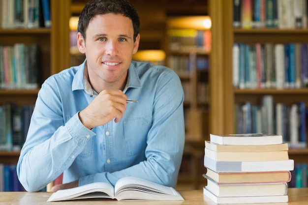 Studente maturo sorridente che studia allo scrittorio delle biblioteche