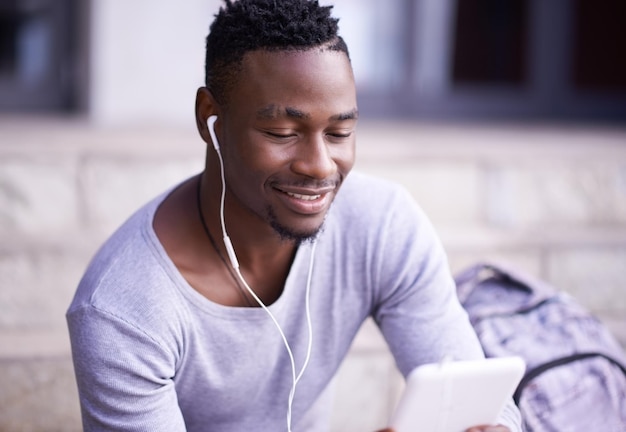 Studente nero e online in città con tablet per informazioni sull'orario universitario o lezioni Allievo maschio tecnologia digitale e internet con musica sui gradini del college felice e leggendo ebook sull'app