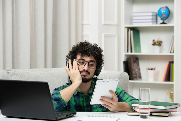 Studente online carino giovane ragazzo che studia al computer con gli occhiali in camicia verde stanco e annoiato