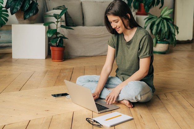 Studente seduta sul pavimento che usa un portatile per studiare online