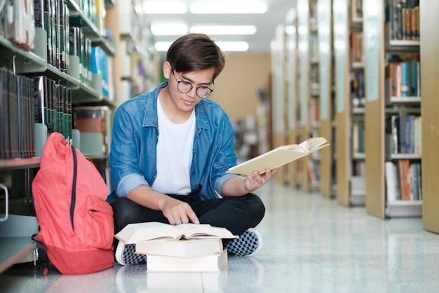 Studente seduto e che studia in biblioteca