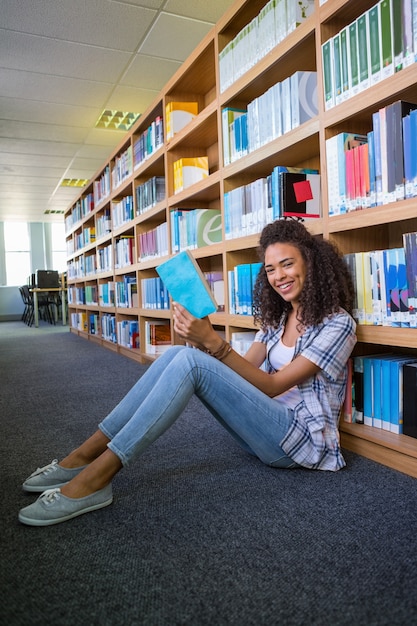 Studente seduto sul pavimento nella lettura della biblioteca