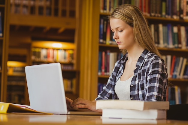 Studente serio che lavora al computer portatile in biblioteca