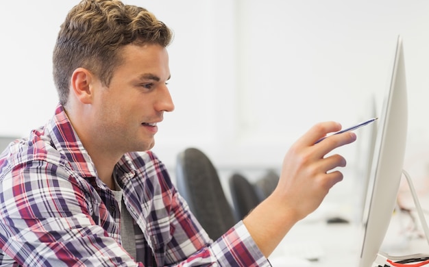 Studente sorridente bello che indica al computer