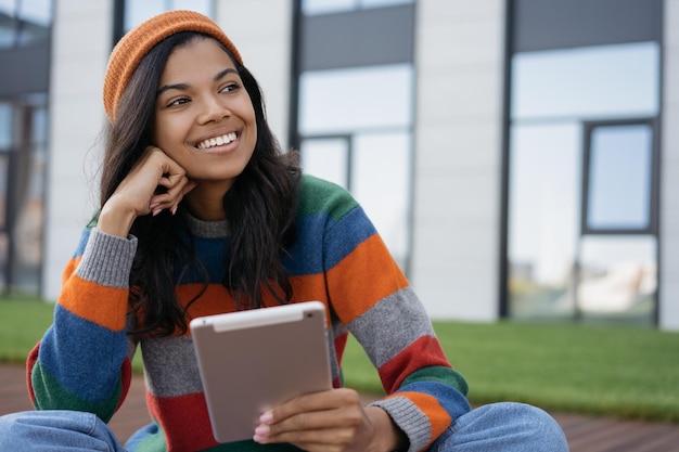 Studente sorridente che studia utilizzando tablet digitale seduto nel concetto di istruzione del campus universitario