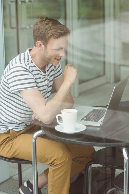 Studente sorridente che utilizza computer portatile nel caffè