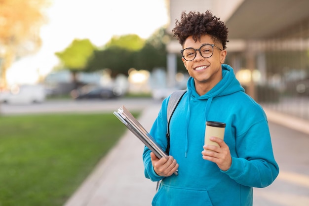 Studente sorridente con il caffè e i fascicolari