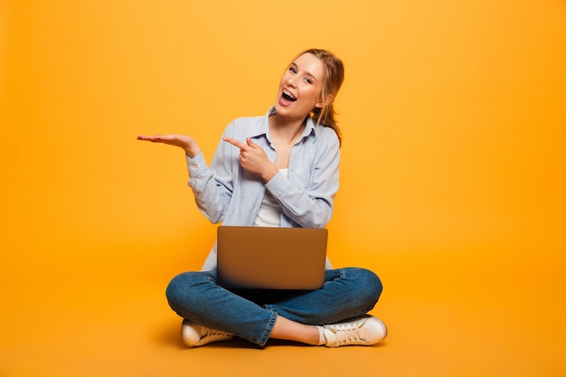 Studente sorridente della giovane signora che usando indicare del computer portatile