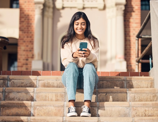 Studente sorridente o ragazza con il telefono sulle scale per la comunicazione Rete 5g o app di notizie sui social media che legge all'aperto Cellulare felice o donna con smartphone per il networking di siti Web di fumetti o post di blog