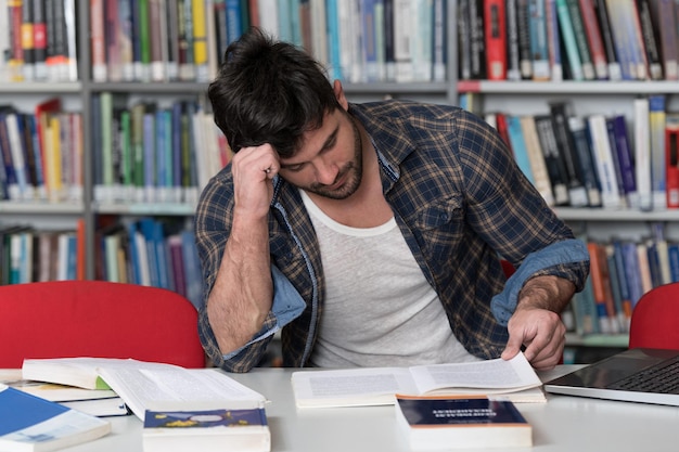 Studente stressato al liceo seduto al banco della biblioteca