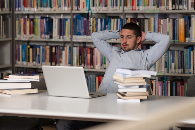 Studente stressato di scuola superiore seduto alla scrivania della biblioteca Profondità di campo ridotta